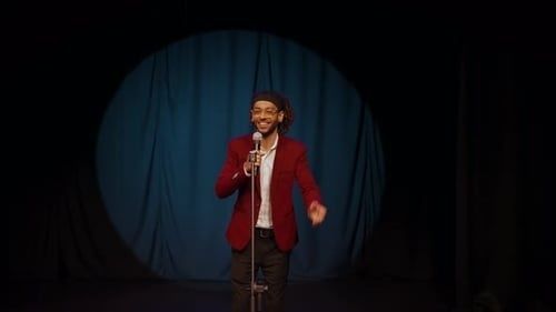 Komiek met microfoon in de spotlights voor een blauw theatergordijn
