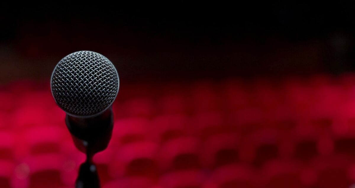 Microfoon op een rood verlicht podium voor een komische voorstelling